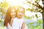 Mother and child are hugging and having fun outdoor in nature - photo with sun flare.