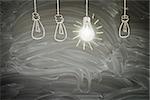 idea concept - row of light bulbs with bright glowing one on blackboard with copy space
