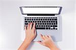 Someones hands and laptop on white desk, top view workspace