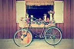 Old bicycle and flowers parked near window of farmhouse at countryside in vintage style