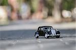 Black classic toy car on the road. Shallow depth of field.