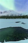 Northern lights is reflected in the water of the hidden river. Lakselva River, Lakselvdalvegen, Lyngen Alps, Troms, Norway, Lapland, Europe.