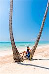 Juanillo Beach (playa Juanillo), Punta Cana, Dominican Republic. Woman under high palm trees on the beach (MR)