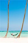 Juanillo Beach (playa Juanillo), Punta Cana, Dominican Republic. Woman relaxing on a hammock on a palm-fringed beach (MR).