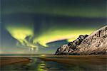 Sandy beach and snowy peaks framed by the Northern Lights in the polar night Ersfjord Senja Tromsø Norway Europe