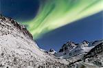 Northern lights and stars on the snowy peaks along the National Tourist Route Bergsbotn Senja Tromsø Norway Europe