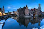 The medieval Belfry and historic buildings are reflected in Rozenhoedkaai canal at dusk Bruges West Flanders Belgium Europe