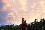 Young woman outdoors at twilight, looking up in thought