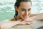 Woman in swimming pool at edge resting head on arms