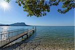 Sun shining on Lake Garda (Lago di Gardo) with wooden jetty in the summer at Garda in Veneto, Italy