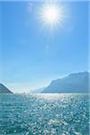 Windsurfing on Lake Garda with with sun in blue sky at Torbole in Trentino, Italy