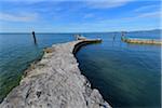 Stone harbor wall with a pier on Lake Garda at Punta San Vigilio in Garda, Veneto, Italy