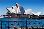 Iron railing and seawall with the Sydney Opera House and a ferry leaving the terminal in Sydney Harbour on a sunny day in Sydney, Australia