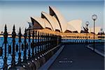 Railing and seawall with paved road leading to the Sydney Opera House in Sydney, Australia