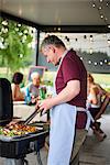Mature man barbecuing on patio at family lunch