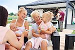 Three generation women with children on laps at family lunch on patio