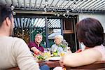 Over shoulder view of senior woman and mature man at family lunch on patio