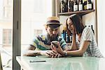 Couple looking at smartphone at bar table