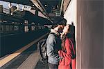 Young couple standing on train platform, kissing