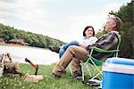 Mature couple sitting in camping chairs beside lake