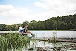 Mature couple relaxing on jetty beside lake