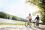 Mature couple cycling beside lake