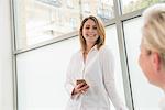 Businesswomen talking and using mobile phone in office