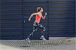 Young female runner speed running along sidewalk