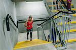 Young female runner running up indoor stairway