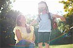 Mature woman with son pretending to be pilot with arms open in sunlit garden