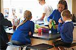 Mother pouring juice for her school children in kitchen