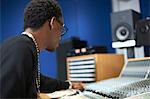 Young male college student at sound mixer in recording studio