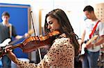 Young female college student playing violin in recording studio