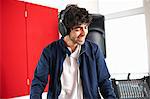 Young male college DJ student listening to music on headphones