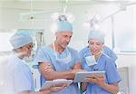 Surgeons and nurse using clipboard and digital tablet in operating room