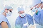 Focused surgeons and anesthesiologist preparing patient for surgery in operating room