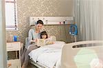 Mother reading book with girl daughter in hospital room