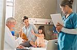 Doctor making rounds, gesturing with girl patient in hospital room