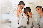 Female doctor using digital thermometer in ear of girl patient in examination room