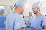 Male surgeons with digital tablet talking in operating room