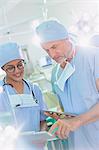 Surgeons with digital tablet and clipboard talking in operating room