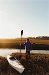 Woman kayaker on riverbank at sunset, Morro Bay, California, USA