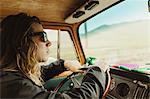 Long haired young man in shades driving vintage vehicle
