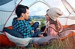 Couple relaxing in tent, rear view