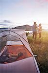 Couple standing near tent, drinking hot drinks, looking at view, Heeney, Colorado, United States