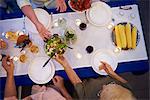 Group of people sitting at table, about to serve food, overhead view