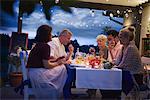 Group of people outdoors, sitting at table, enjoying meal