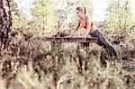 Young woman in rural setting, exercising, doing push-ups on bench