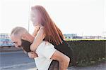 Man giving red haired woman piggyback