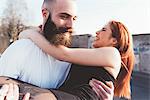 Bearded man carrying smiling woman in arms